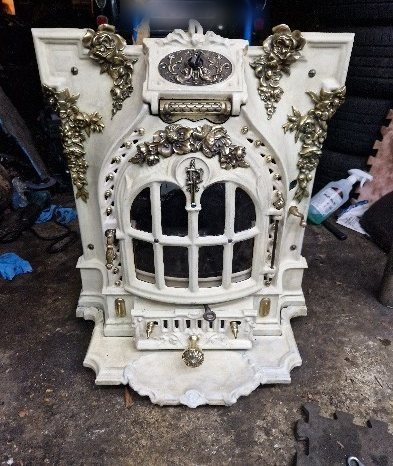 The restored Deville DPF 600 fireplace with its door closed, in white enamel with polished brass details
