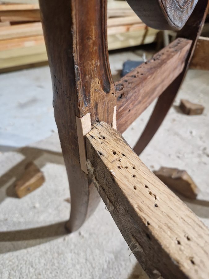 New joinery repair to a side rail where the old timber was damaged; the small holes are tack holes from the old upholstery